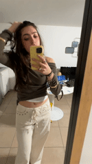 Woman takes mirror selfies with yellow phone in Saint-Ouen