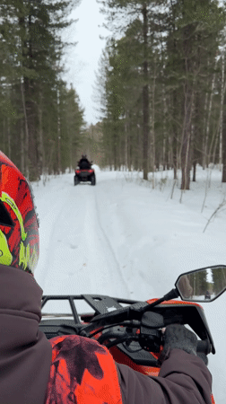 ATV rider navigates snowy forest path near Izluchinsk
