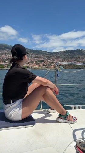 Woman sits on boat looking toward shore near Funchal