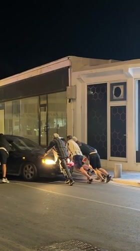 Evening street activities in Paphos: car push, scooter tricks