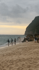 Beachgoers enjoy waters at Kuta Selatan under cloudy skies
