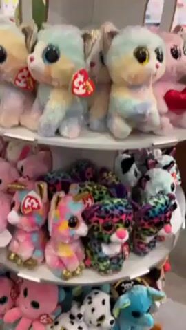 The video shows a multi-tiered rotating display shelf filled with Ty Beanie Boos stuffed animals. The top shelf contains pastel-colored creatures, while the middle shelf features unicorns with gold hooves, a pink octopus, and Dalmatian puppies. The bottom shelf has frogs and other animal designs. The camera slowly pans from top to bottom.