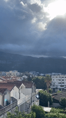 Dramatic sunbeams pierce storm clouds over Budva cityscape