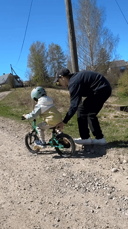 Child learns bicycle riding with adult assistance in Rezekne