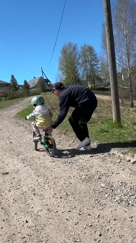 Child learns bicycle riding with adult assistance in Rezekne
