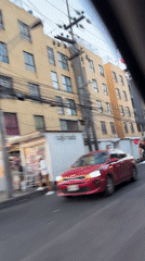 Vehicle passenger records street view of tan buildings in Mexico City