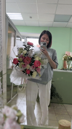 Woman takes flower bouquet selfies in Izhevsk mirror