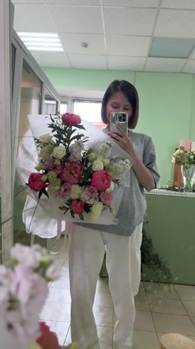 Woman takes flower bouquet selfies in Izhevsk mirror
