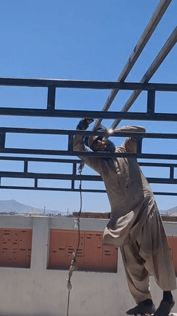 Construction worker welds metal beams on Quetta rooftop