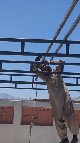 Construction worker welds metal beams on Quetta rooftop