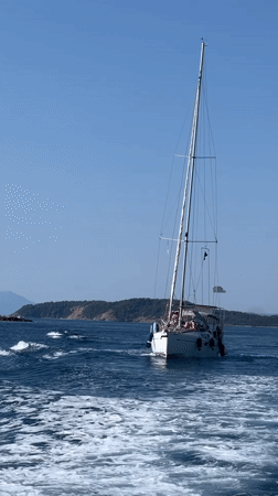 Sailing past a rocky Greek island under clear skies
