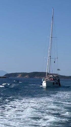 Sailing past a rocky Greek island under clear skies