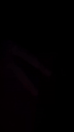 Person observed resting with hand covering face in low-light