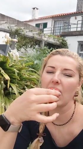 Woman eats strawberry, cattle graze in Ribeira Grande