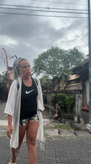 Woman observed making gestures, touching foliage in Kuta street