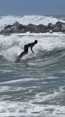 Surfer rides waves near Tel Aviv breakwater