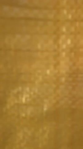The video shows a close-up of a yellow woven plastic bag. The camera shifts slightly, revealing more of the bag's surface. It then focuses on a faded brown mark on the bag before going out of focus.