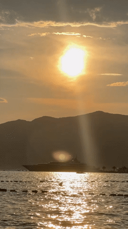 Summer evening at a harbor: boats, sunset, and people out.