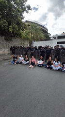 Small group stages sit-down protest facing riot police in Caracas