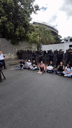 Small group stages sit-down protest facing riot police in Caracas
