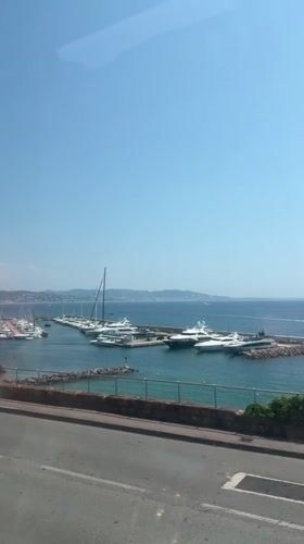 Calm day at Cannes harbor, yachts docked under clear skies.