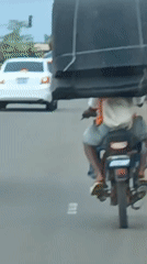 Motorcyclist carries oversized black object through Rido, Nigeria