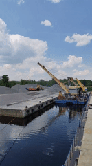 Barge crane loads materials as cruise ship passes Yakhroma waterway