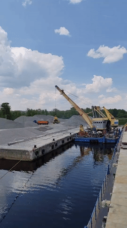 Barge crane loads materials as cruise ship passes Yakhroma waterway