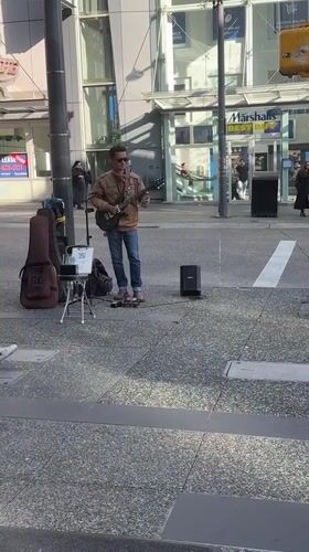 Street musician performs electric guitar near Vancouver's Pacific Centre