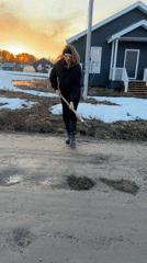 Woman repairs potholes with shovel in rural Russian village