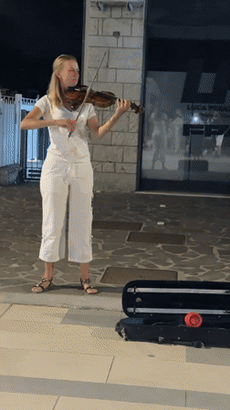 Violin performance on cobblestone streets after dark.