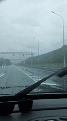 Gray train passes through rainy Adlerskiy, Russia
