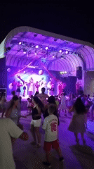 Evening stage performance with dancing under purple lights in Caorle