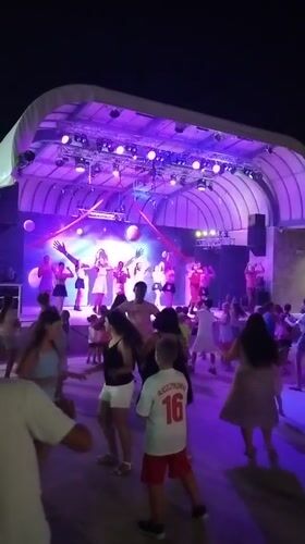 Evening stage performance with dancing under purple lights in Caorle