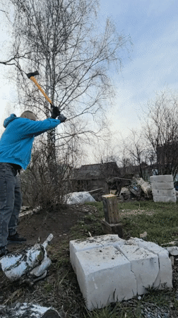 Man splits wood with axe in Noviy, Russia