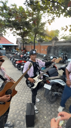 Street musicians perform as tourist enjoys seafood in Kuta