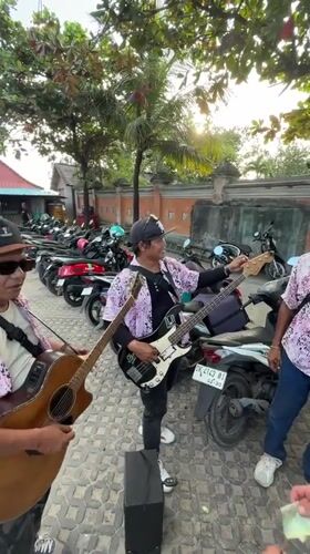 Street musicians perform as tourist enjoys seafood in Kuta