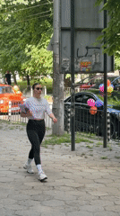 Woman walks sidewalk in Pleven carrying purple folder