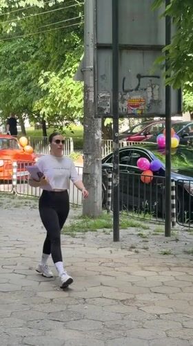 Woman walks sidewalk in Pleven carrying purple folder