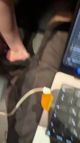 The video opens with a close-up shot of a person's lap, where a silver laptop is open. A white charging cable is plugged into the laptop, and a small piece of orange food is visibly stuck to the charging block. The laptop screen displays a list of digital files or project names, including "GPT-Research," "Yandex LLM," and "Citation L." Another larger screen or tablet is visible next to the laptop, also displaying a similar list. The keyboard features Cyrillic characters. A bare foot is partially visible in the background, resting on dark fabric.

A quick, blurry transition shows a brightly lit indoor space, possibly a restaurant or cafe, with various lights and ceiling elements. This is followed by a close-up, low-angle selfie of a man with his eyes playfully closed and a slightly puckered expression, appearing amused. Bright overhead lights are visible behind him. The video then cuts back to the initial shot of the laptop, cable, and the orange food. The scene takes place indoors, likely in a cafe or restaurant in Minhang District, China.