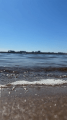 Waves lap sandy shore in Izhevsk under clear skies