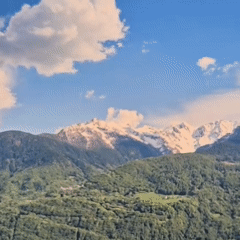 Aerial view over forested mountains with snow-capped peaks beyond