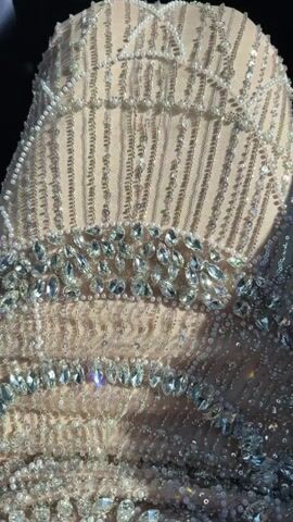The video starts with a close-up shot of a light tan dress covered in beads and rhinestones. The view then transitions to a view from inside a car as it passes a sign that reads "Netflix Amis Paris." The car continues moving, and the view shifts to the Pullman Hotels Joa Royal Casino. The camera continues to move, capturing trees, street lights, and greenery alongside the hotel.