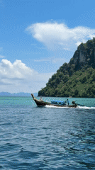 Longtail boat cruises turquoise waters off Ao Nang Thailand