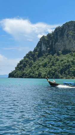 Longtail boat cruises turquoise waters off Ao Nang Thailand