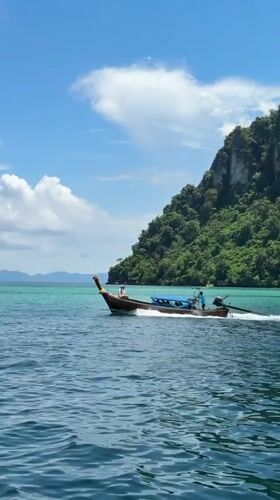 Longtail boat cruises turquoise waters off Ao Nang Thailand