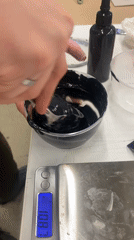 Person stirs black substance in bowl on scale in Moscow
