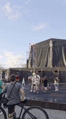 Park event with stage acts, fountain lights, and kids