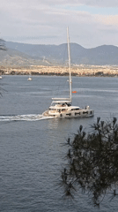 White catamaran sails past Fethiye harbor with mountain backdrop