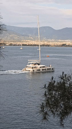White catamaran sails past Fethiye harbor with mountain backdrop